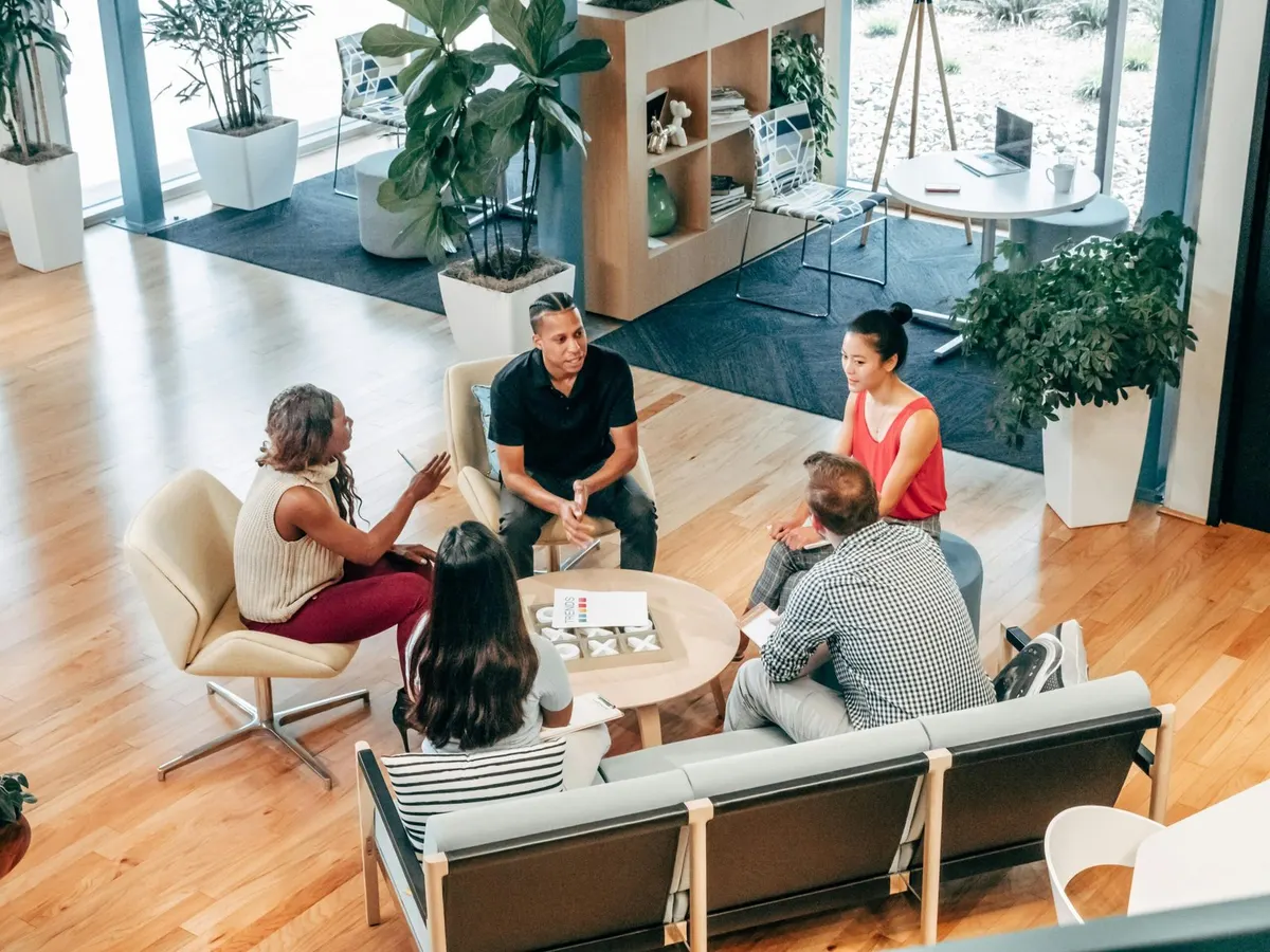 Groupe de personnes en réunion informelle dans un espace de travail partagé et lumineux