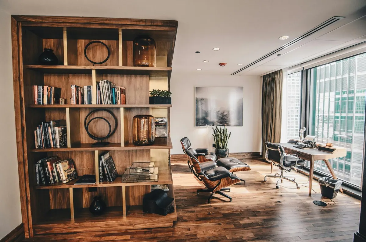 Bureau rénové avec bibliothèque en bois, fauteuil et grandes fenêtres
